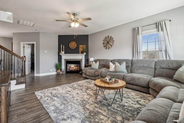 living area featuring visible vents, baseboards, dark wood finished floors, stairs, and a glass covered fireplace