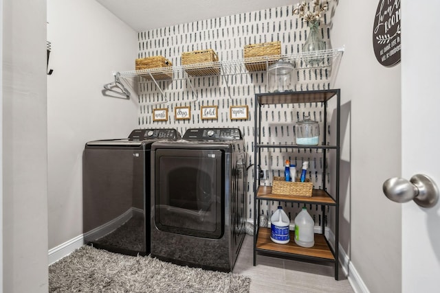 washroom featuring baseboards, separate washer and dryer, and laundry area