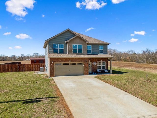 view of front of house featuring a front yard, fence, driveway, an attached garage, and brick siding