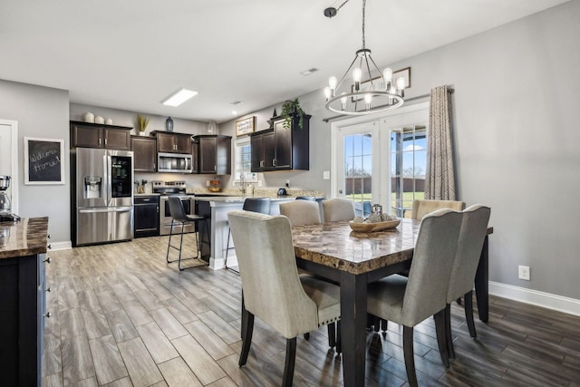 dining area with an inviting chandelier, french doors, baseboards, and wood tiled floor