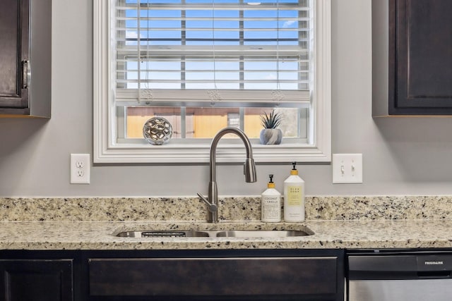 interior details with a sink, dark brown cabinets, light stone countertops, and stainless steel dishwasher