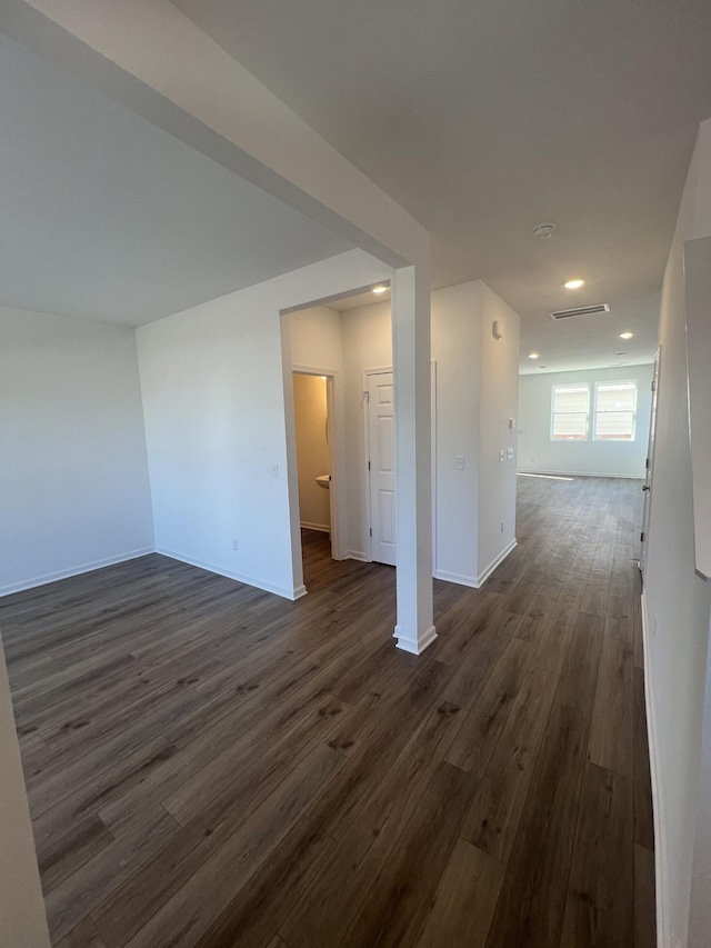 unfurnished room with visible vents, baseboards, and dark wood-style flooring