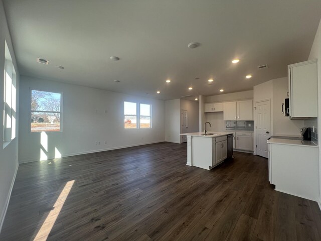 kitchen featuring a center island with sink, visible vents, open floor plan, and dark wood finished floors