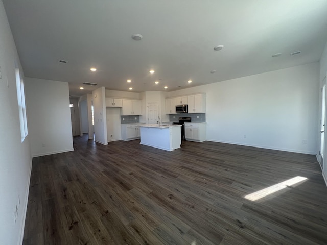 unfurnished living room with dark wood finished floors, visible vents, recessed lighting, and a sink