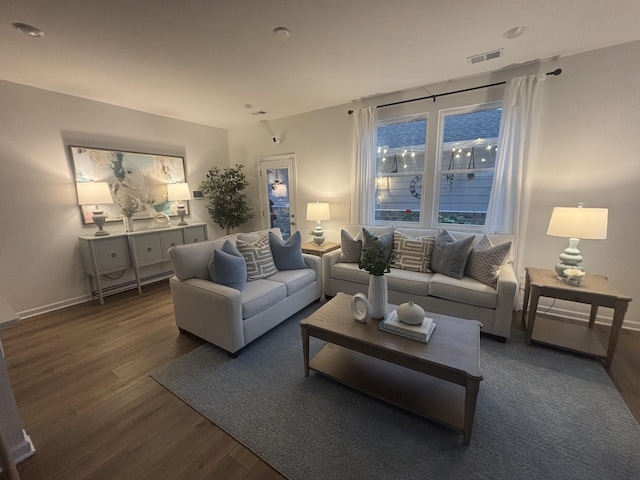 living room with visible vents, baseboards, and wood finished floors