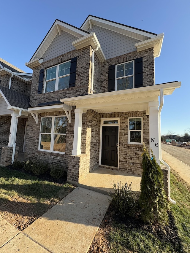 view of front of house with brick siding, covered porch, and a front lawn