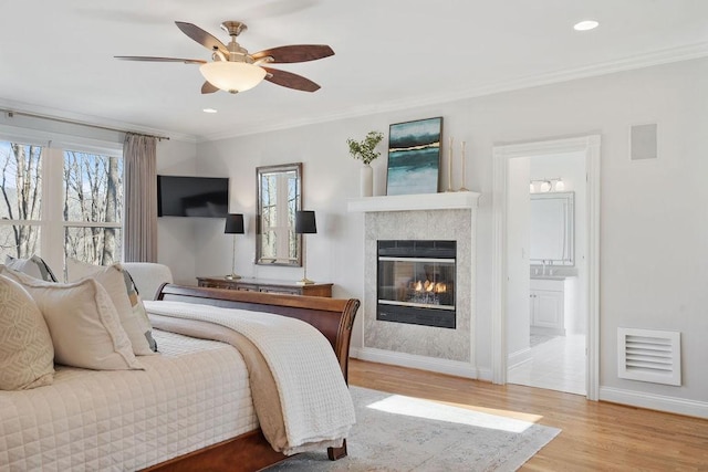 bedroom featuring visible vents, crown molding, a glass covered fireplace, and wood finished floors