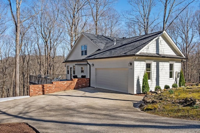 view of home's exterior featuring a garage, roof with shingles, driveway, and fence