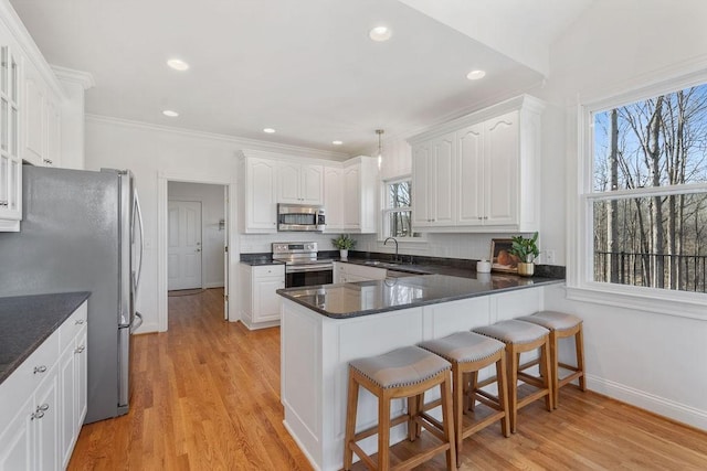 kitchen featuring decorative backsplash, appliances with stainless steel finishes, a peninsula, and a sink