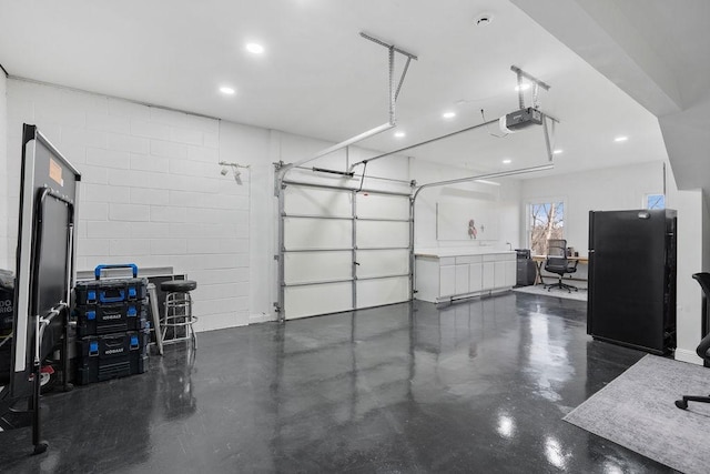 garage with recessed lighting, concrete block wall, and a garage door opener