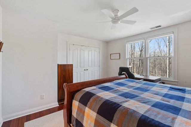 bedroom with visible vents, wood finished floors, a closet, baseboards, and ceiling fan