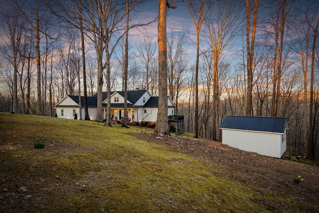 view of front of property featuring a storage unit, an outdoor structure, and a front lawn