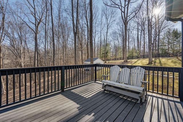 wooden deck featuring an outbuilding, a shed, and fence