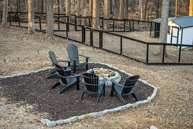 view of yard featuring an outbuilding, fence, and an outdoor fire pit