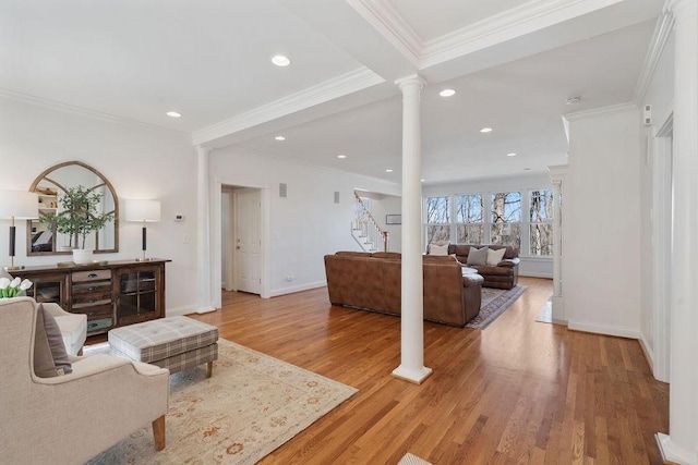 living area with decorative columns, baseboards, crown molding, and light wood finished floors