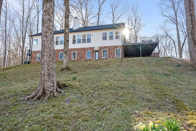 view of front of home featuring a yard, brick siding, and a chimney