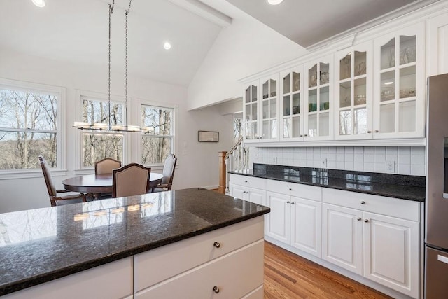 kitchen featuring light wood finished floors, white cabinetry, glass insert cabinets, and vaulted ceiling