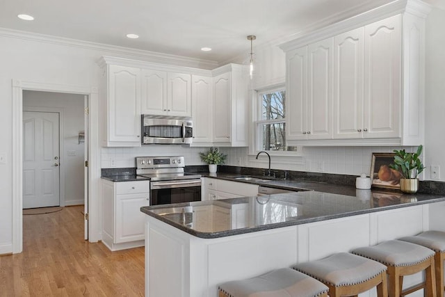 kitchen with white cabinets, appliances with stainless steel finishes, and ornamental molding