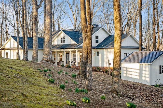 view of front of home with an outbuilding, covered porch, an attached garage, and metal roof