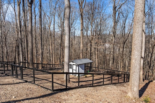 view of yard featuring a view of trees, an outdoor structure, and fence