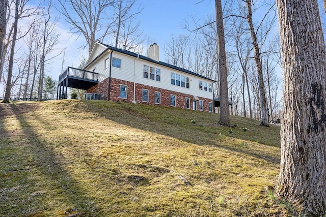 view of front of property with brick siding, a wooden deck, and a chimney