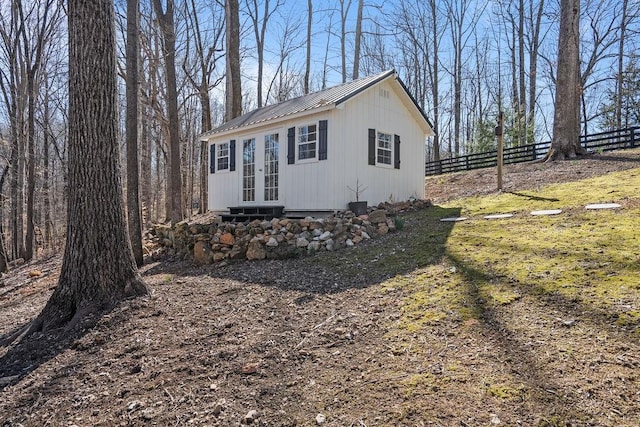 view of outdoor structure featuring an outbuilding, french doors, entry steps, and fence