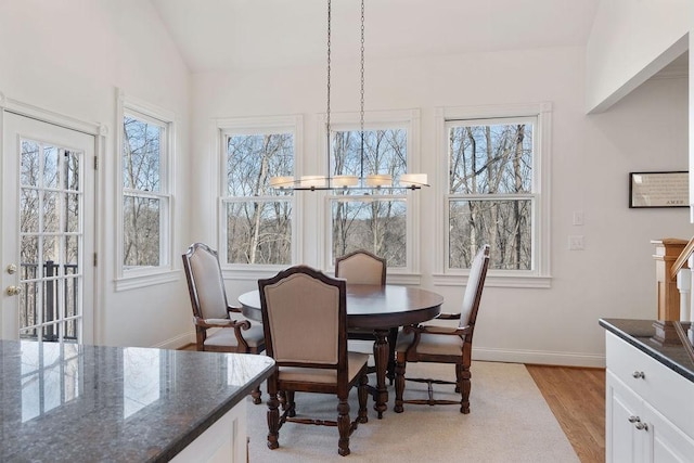 dining room with lofted ceiling, baseboards, and light wood finished floors