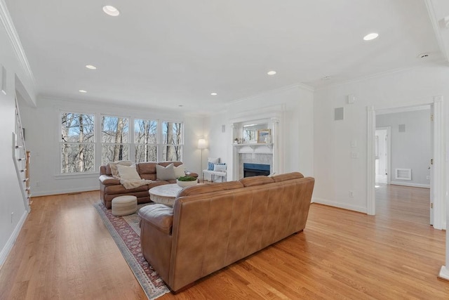 living room with baseboards, a fireplace, light wood-type flooring, and ornamental molding