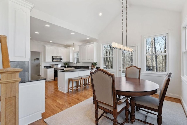 dining room with baseboards, high vaulted ceiling, light wood-style flooring, recessed lighting, and a notable chandelier