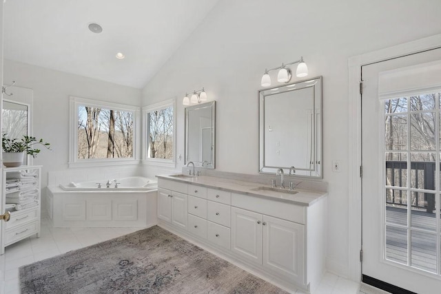 bathroom with tile patterned floors, a sink, double vanity, a bath, and vaulted ceiling