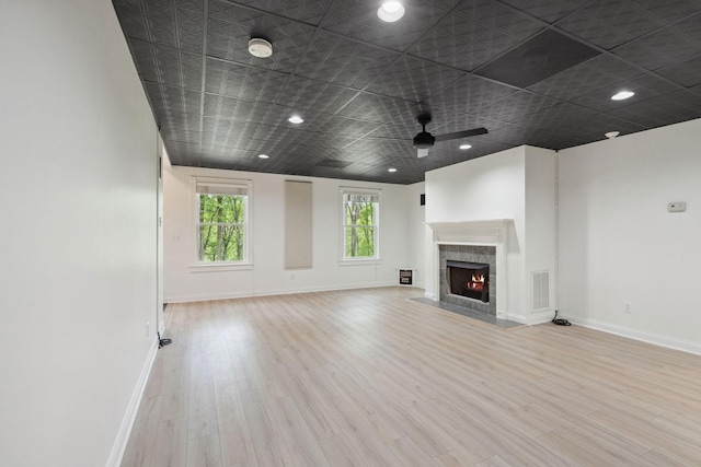 unfurnished living room with baseboards, wood finished floors, visible vents, and a fireplace