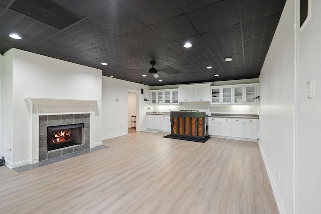 kitchen featuring baseboards, open floor plan, light wood-style floors, and glass insert cabinets