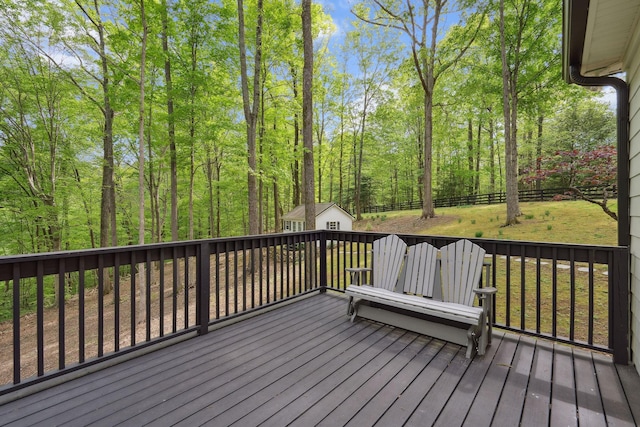 wooden terrace featuring an outdoor structure, a shed, and a fenced backyard