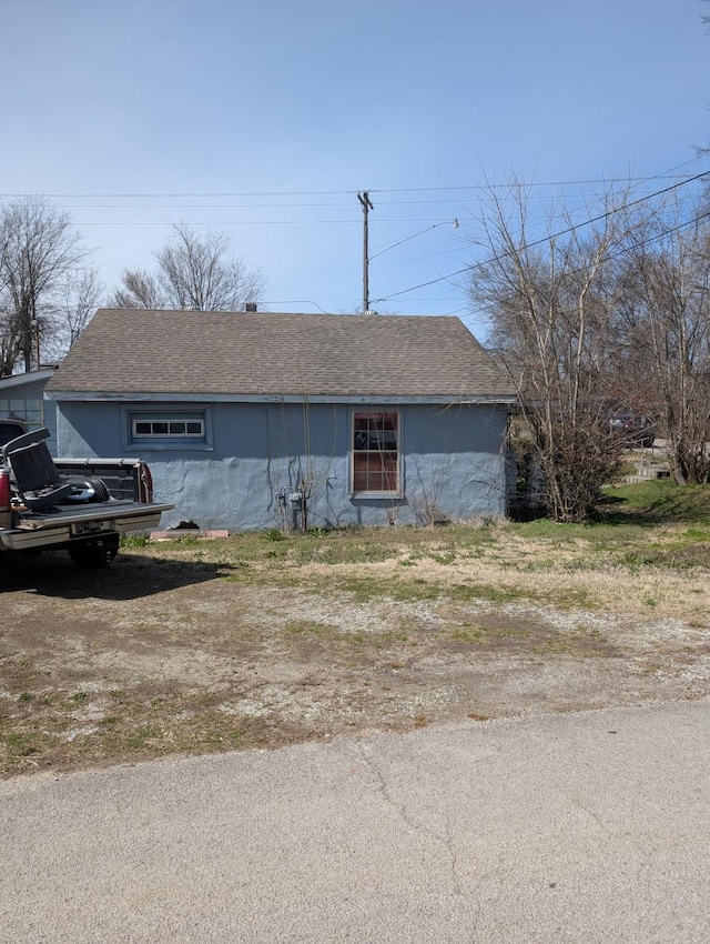 view of front facade with stucco siding and a shingled roof