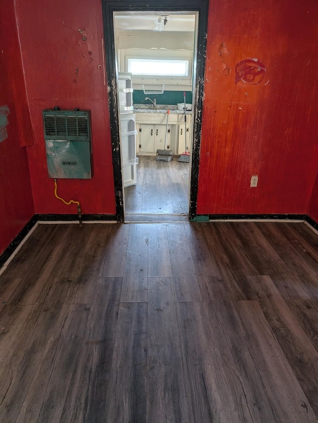 unfurnished room featuring hardwood / wood-style floors, heating unit, and a sink