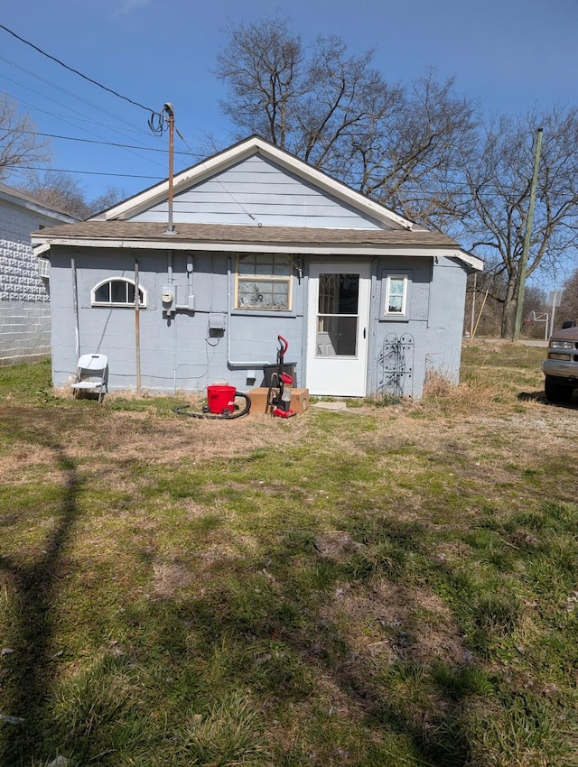 rear view of property featuring a lawn and roof with shingles