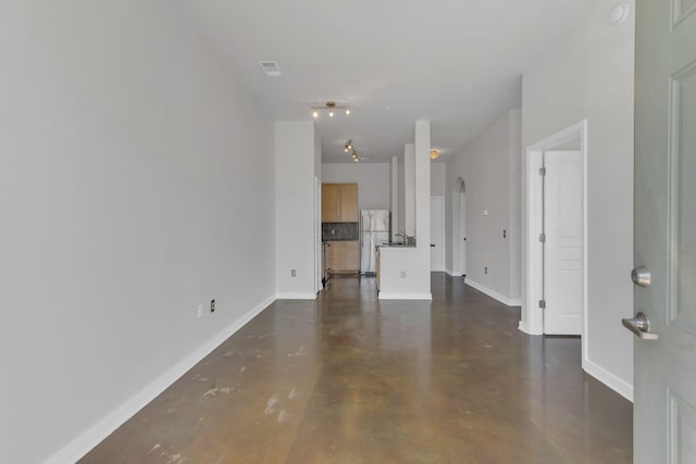 unfurnished living room with baseboards, arched walkways, concrete floors, and visible vents
