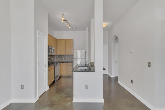 kitchen featuring a sink, finished concrete floors, stainless steel appliances, dark countertops, and backsplash