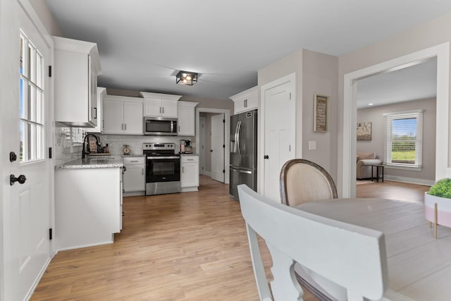 2436 J D Todd Rd, Murfreesboro, TN 37129 - kitchen with stainless steel appliances, a sink, light wood-style flooring, tasteful backsplash, and white cabinetry