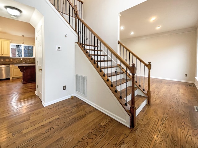 staircase featuring wood finished floors, visible vents, and baseboards