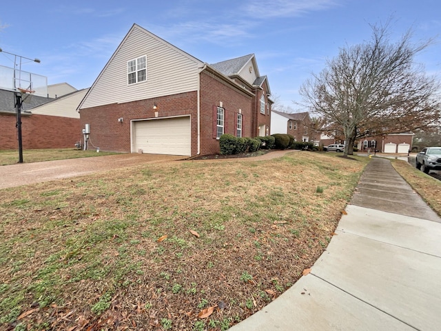 view of side of home with brick siding, a yard, driveway, and a garage