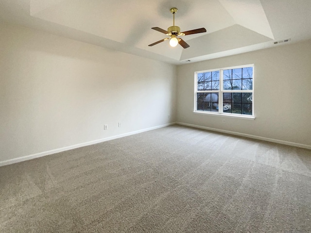 unfurnished room featuring visible vents, ceiling fan, baseboards, carpet, and a tray ceiling