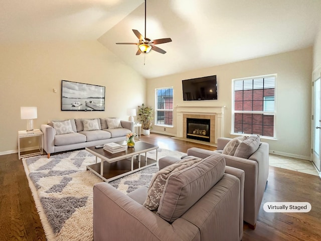 living area with wood finished floors, baseboards, lofted ceiling, ceiling fan, and a tile fireplace