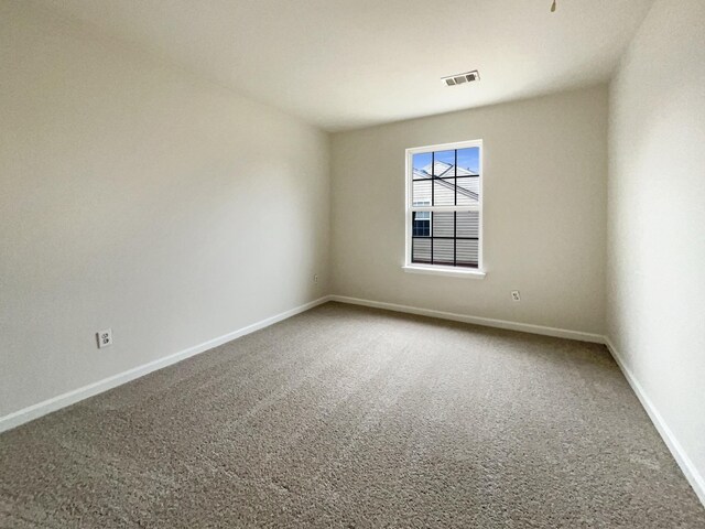 empty room featuring visible vents, carpet flooring, and baseboards