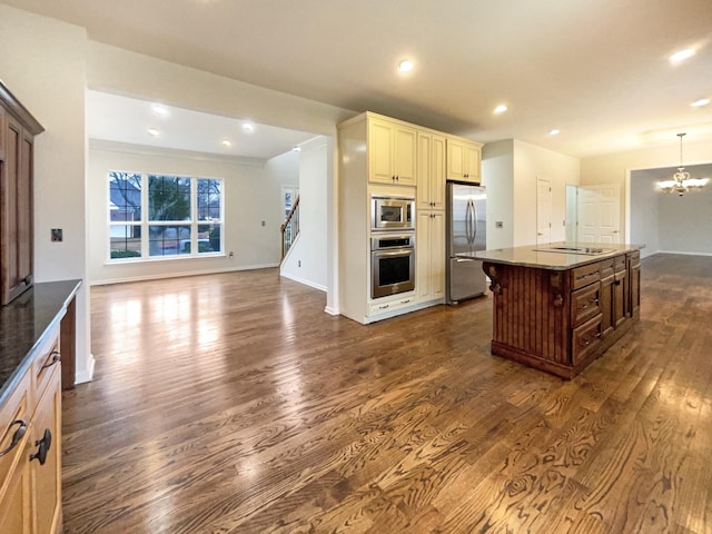 kitchen featuring an inviting chandelier, dark wood-style flooring, stainless steel appliances, cream cabinets, and open floor plan