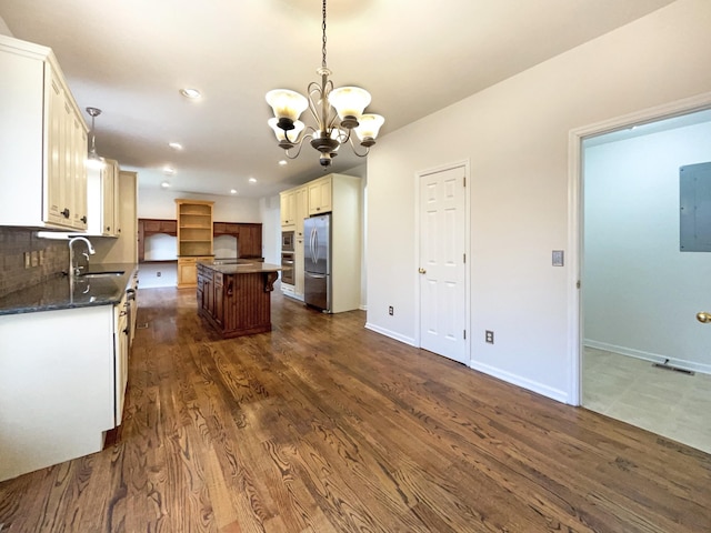 kitchen with a sink, a center island, appliances with stainless steel finishes, decorative backsplash, and dark wood-style flooring