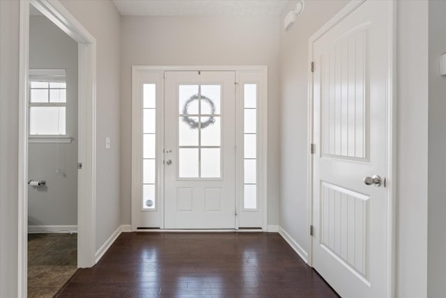 entryway with dark wood finished floors and baseboards