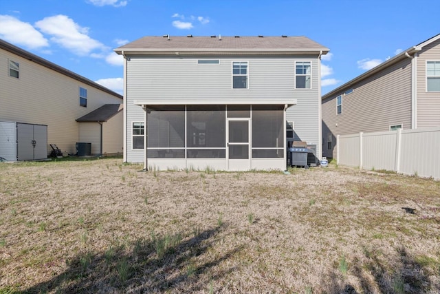 rear view of house featuring a yard, fence, central AC, and a sunroom