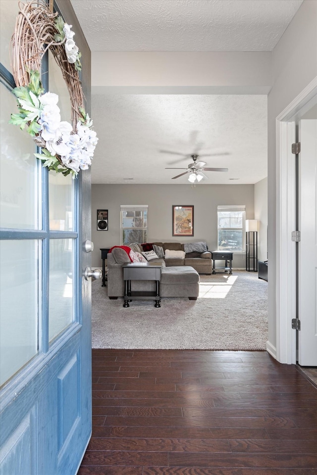 living area with dark wood finished floors, ceiling fan, and a textured ceiling