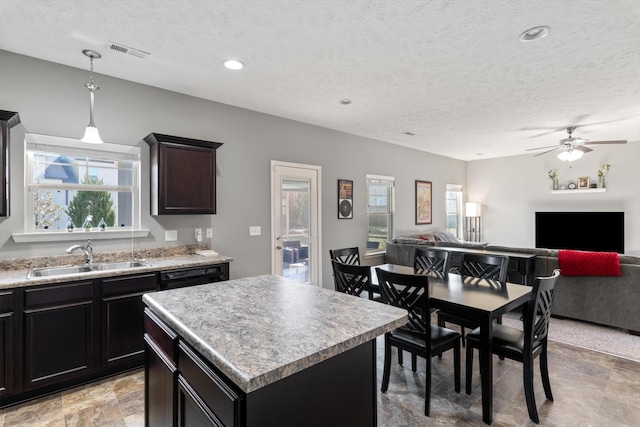 kitchen with a sink, visible vents, a center island, and light countertops